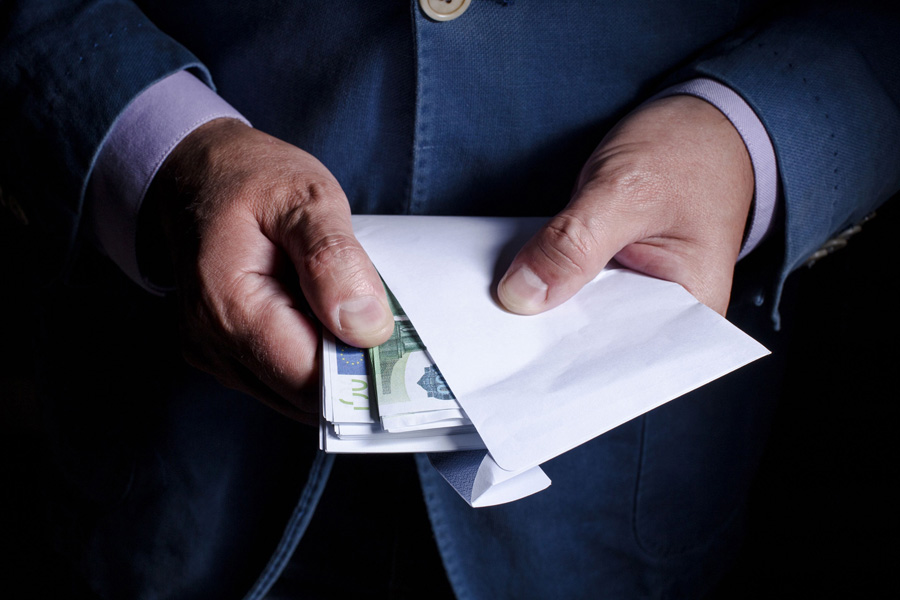 Unas manos de un hombre con un sobre con dinero.